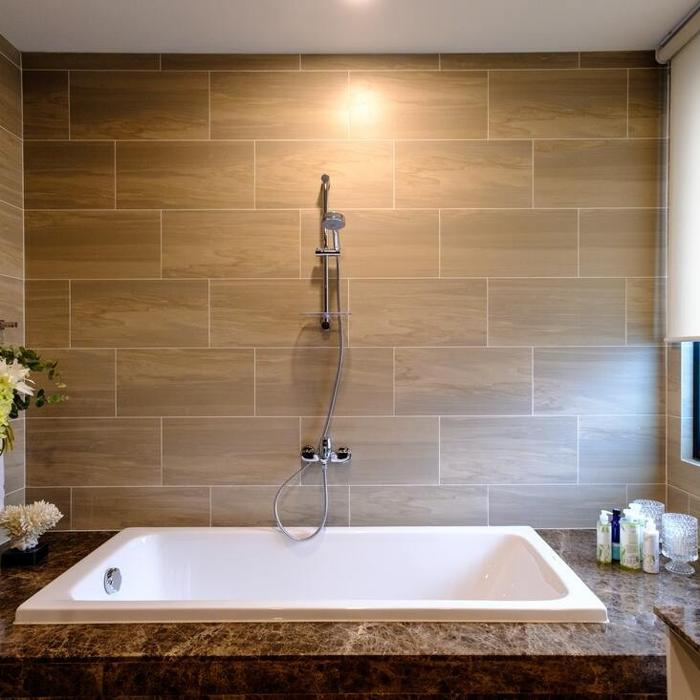 Bathroom with beige tiles and a white bathtub