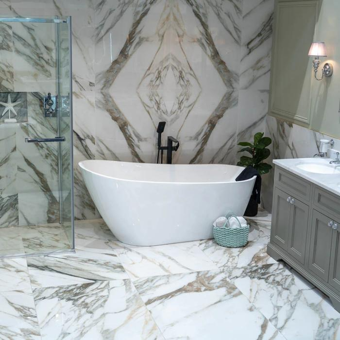 Marble walls and flooring adorn a bathroom featuring a freestanding bath