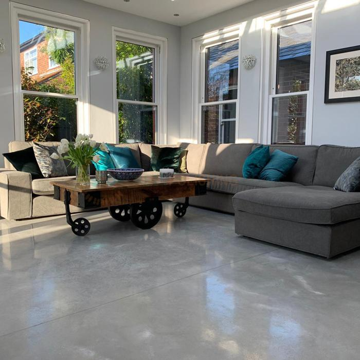 Sunlit room with concrete flooring and grey sofa