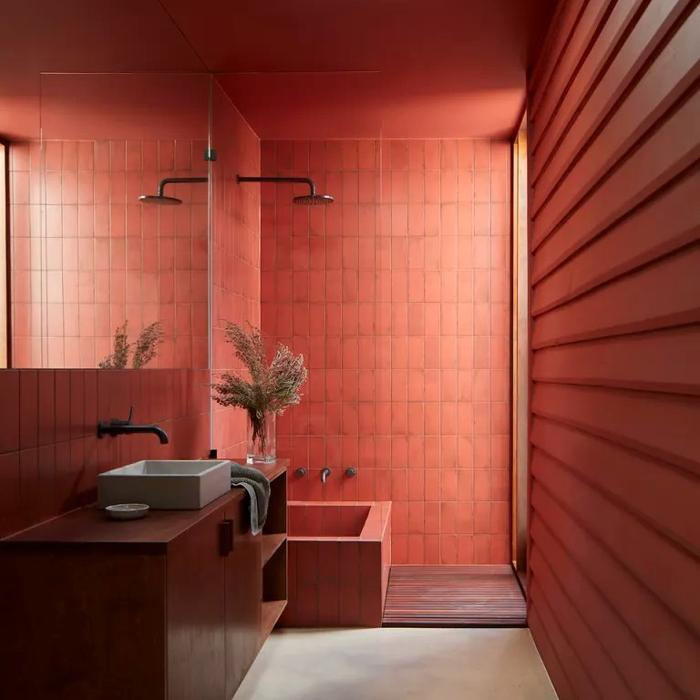 Deep red tiles covering bathroom walls and bathtub