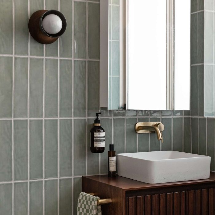 Square sink with brass tap and green wall tiles