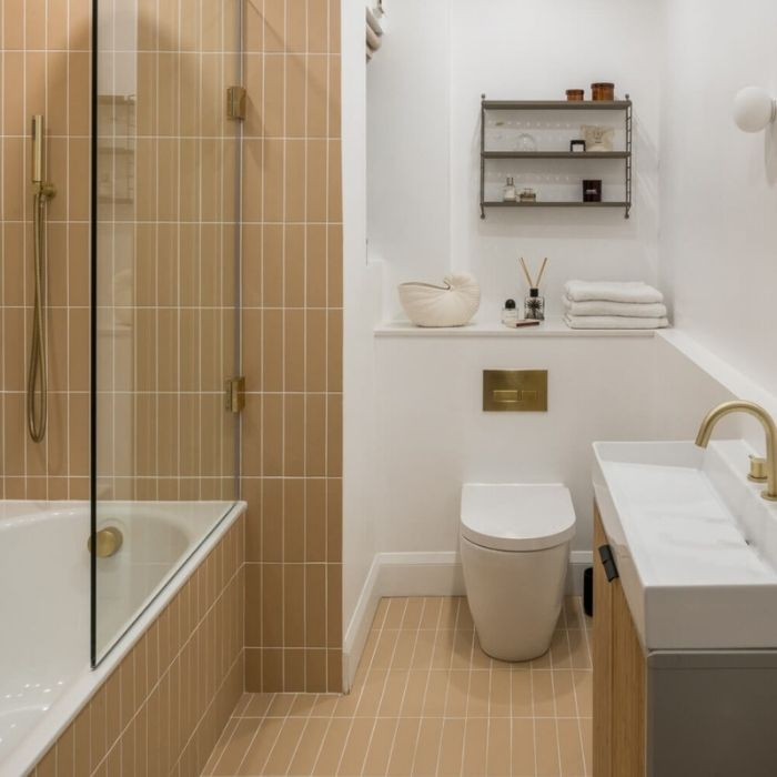 Compact bathroom with beige vertical tiles and brass fixtures