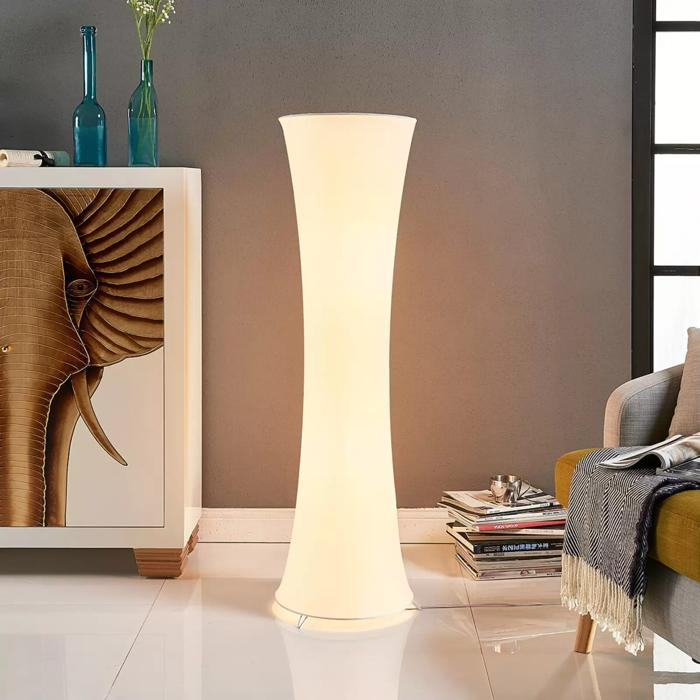 White cylindrical floor lamp beside elephant artwork and sofa