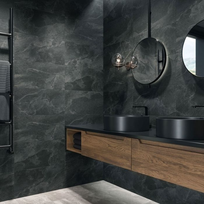 Black stone tiles with wooden vanity and round mirrors