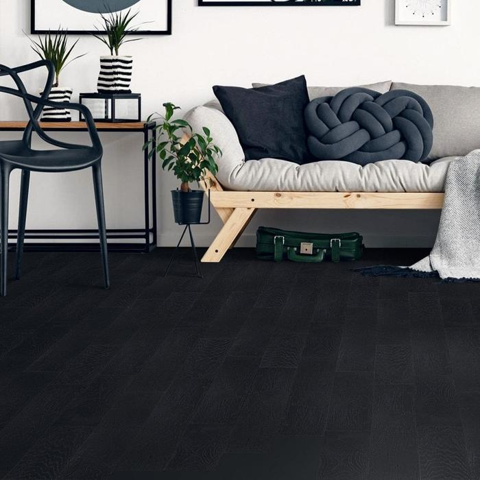 A stylish living room featuring sleek black hardwood floors and a modern couch. 