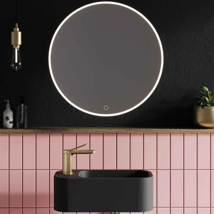 Black sink with gold tap and pink wall tiles