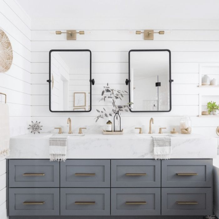 Double sink vanity with white shiplap walls and gold fixtures