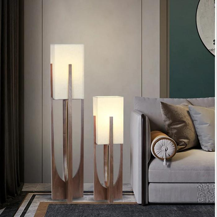 Two wooden floor lamps with white shades beside grey sofa