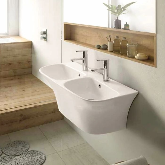 Double white sink with wooden accents and light walls