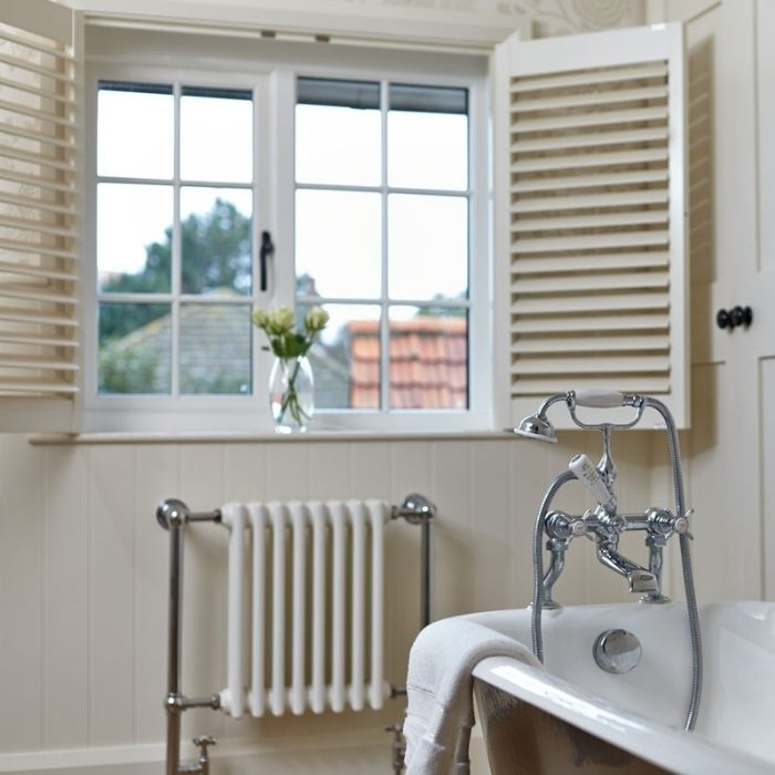 Cottage-style window with white shutters and vintage bath