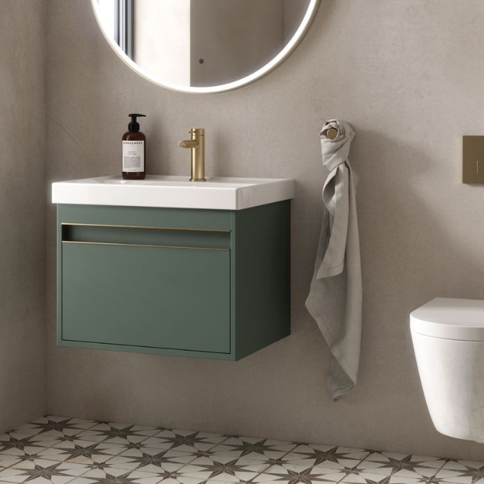 Small green vanity with brass tap and patterned floor tiles