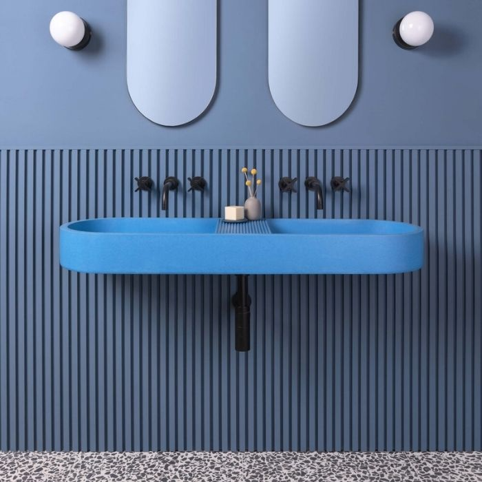 Long blue sink with black taps and blue wall panels