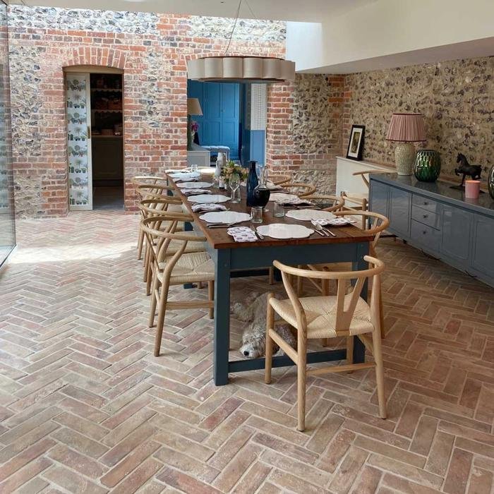 A rustic dining room with herringbone terracotta tiles underneath