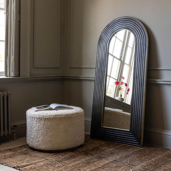 Arched mirror with dark frame on floor