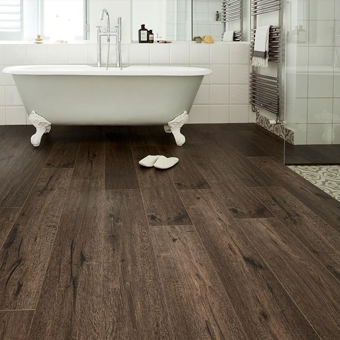 Bathroom with dark wood floor tiles beneath a white tub