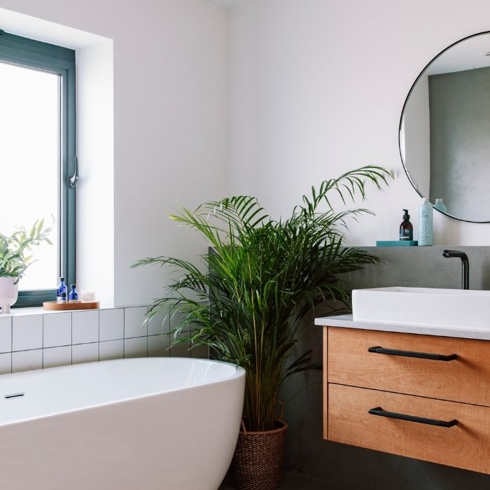 White square tiles with a wooden vanity and green plant in bathroom