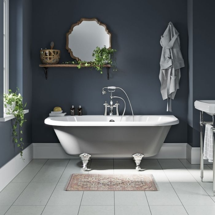 Dark blue painted walls with white clawfoot bathtub and light floor tiles