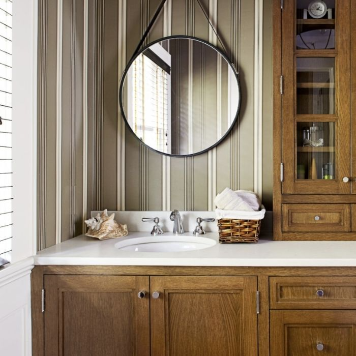 Wooden vanity with a round mirror and striped walls