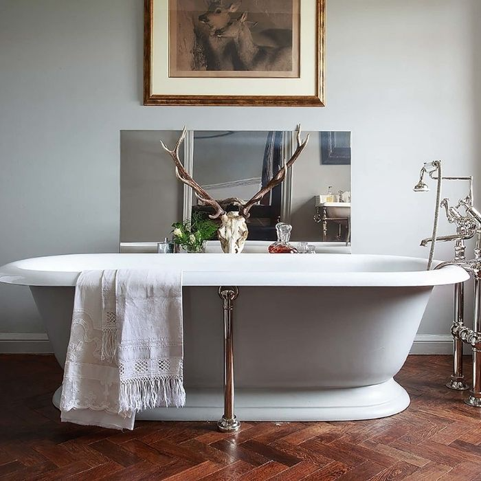 Freestanding bathtub with antlers decoration and wood flooring