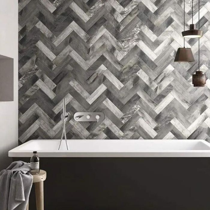 Herringbone pattern tiles behind a freestanding bathtub