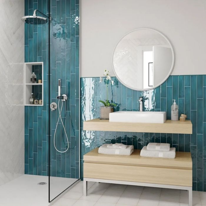 Blue wall tiles with wood vanity in a bright bathroom