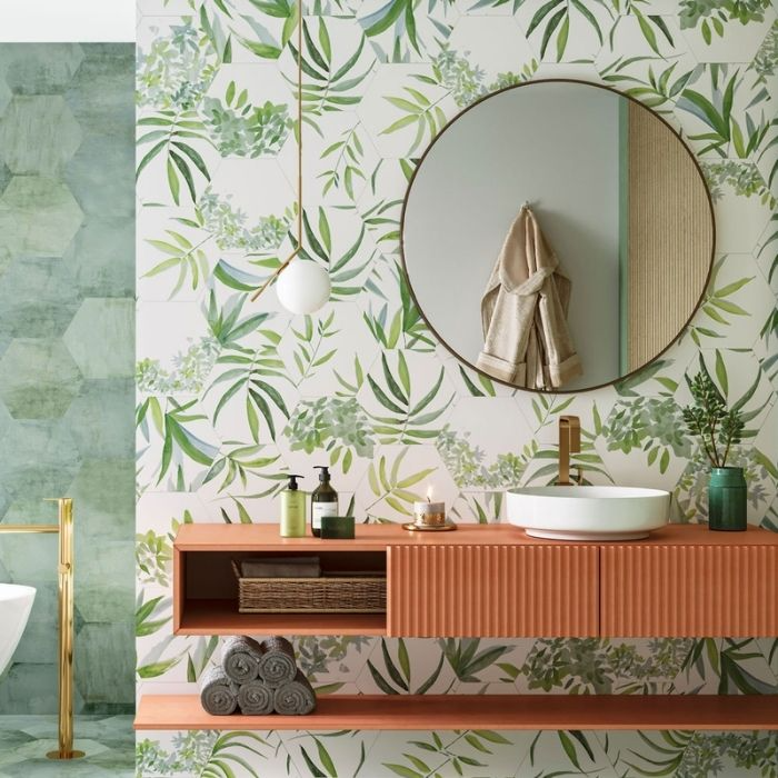 Green leafy wallpaper in a bathroom with a round mirror