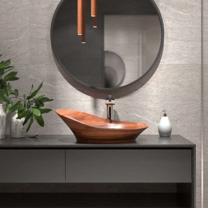 Wooden sink with dark grey countertop and circular mirror