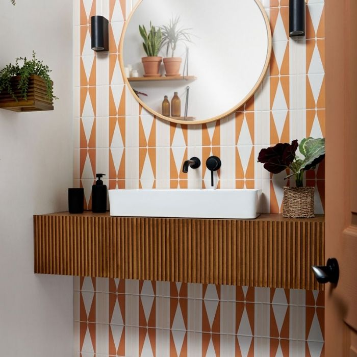 White sink with geometric orange and white wall tiles