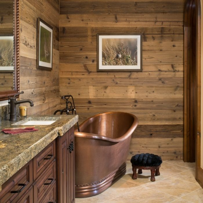 Copper bathtub with wood panelled walls and granite countertop