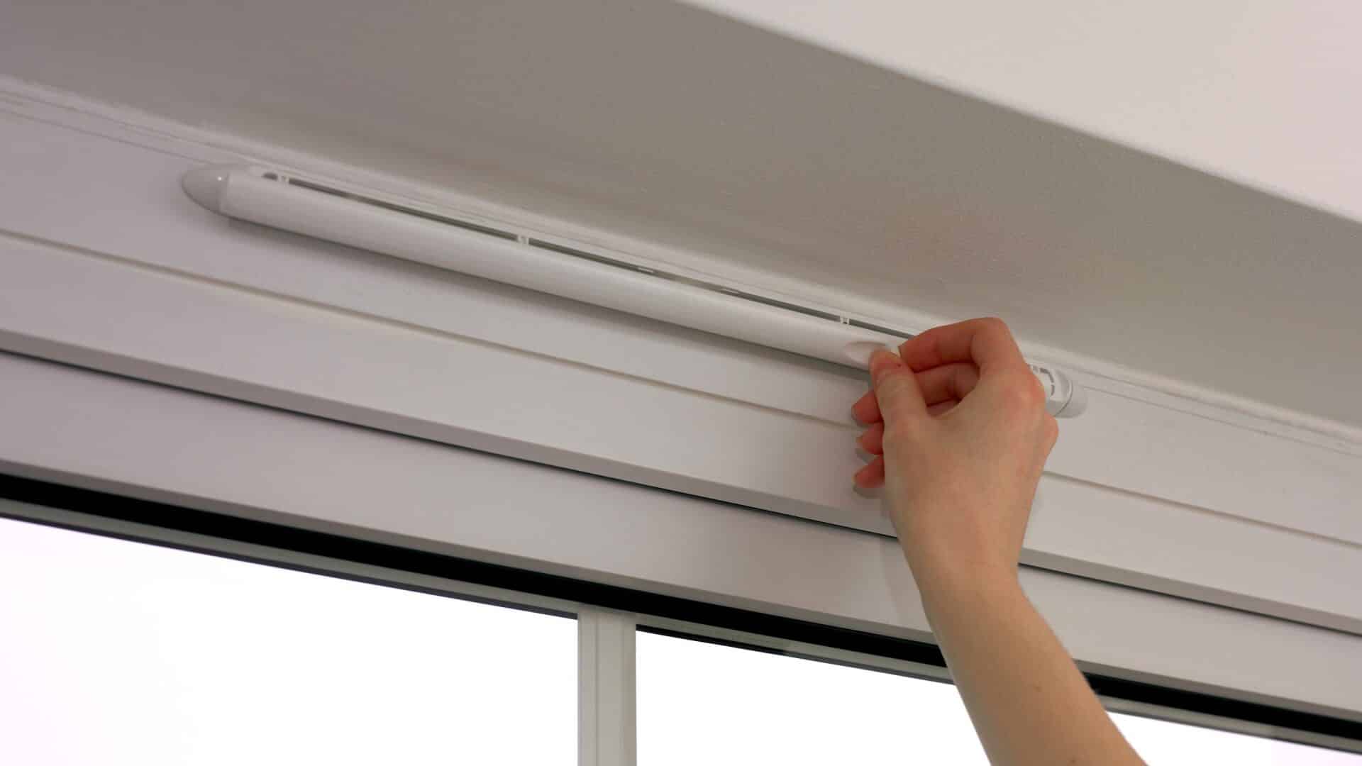 Adjusting bathroom window blinds for optimal natural light.