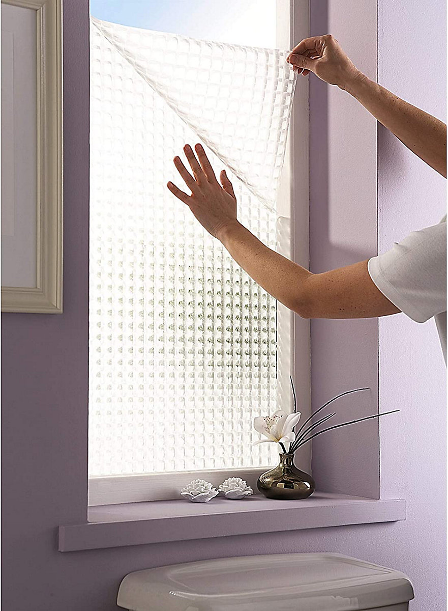 Applying window film for privacy in a bathroom window.