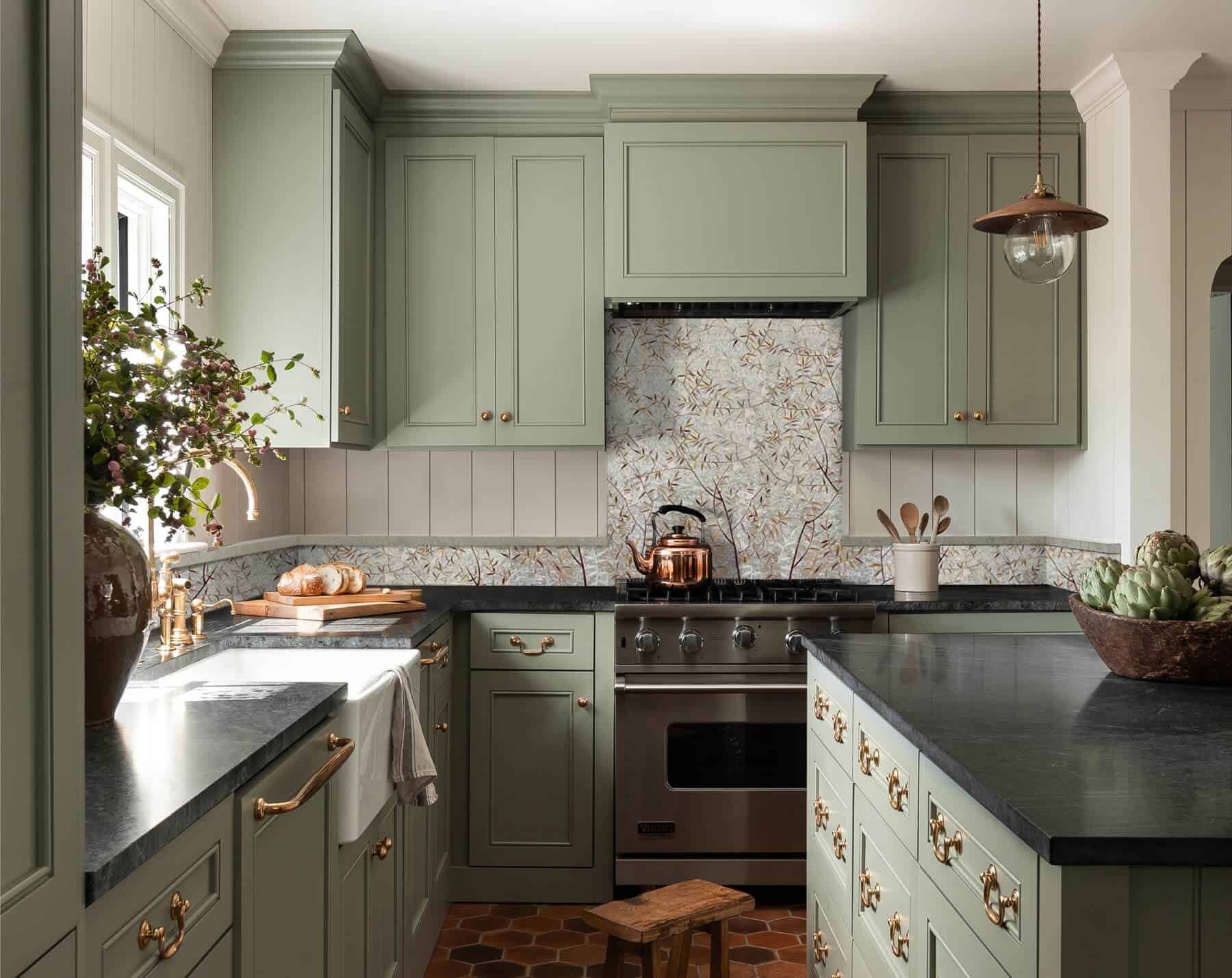 Elegant kitchen with floral backsplash and sage green cabinets.