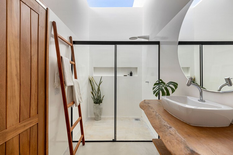 Modern bathroom with skylight, wooden elements, and glass partitions.