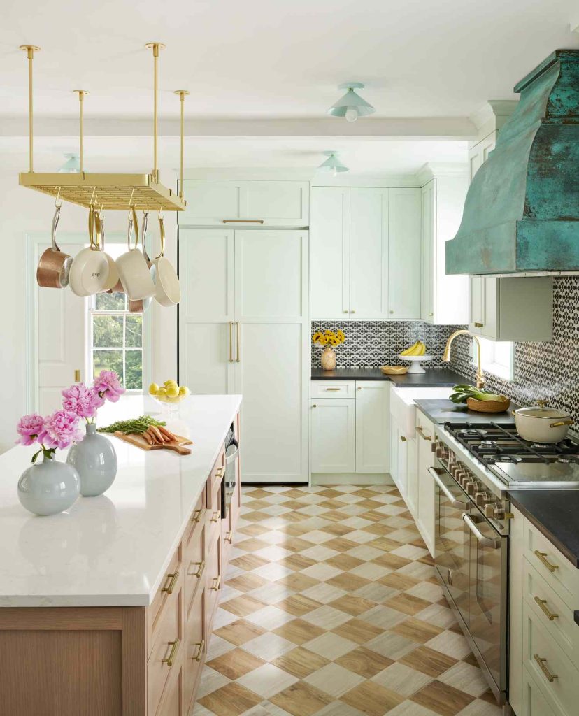 Patterned tile backsplash complements checkerboard floor in stylish kitchen.