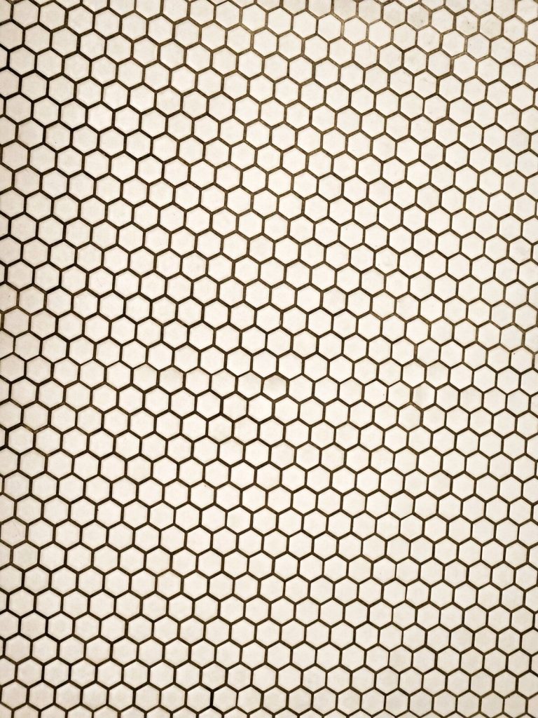 Hexagonal white floor tiles laid with dark grout