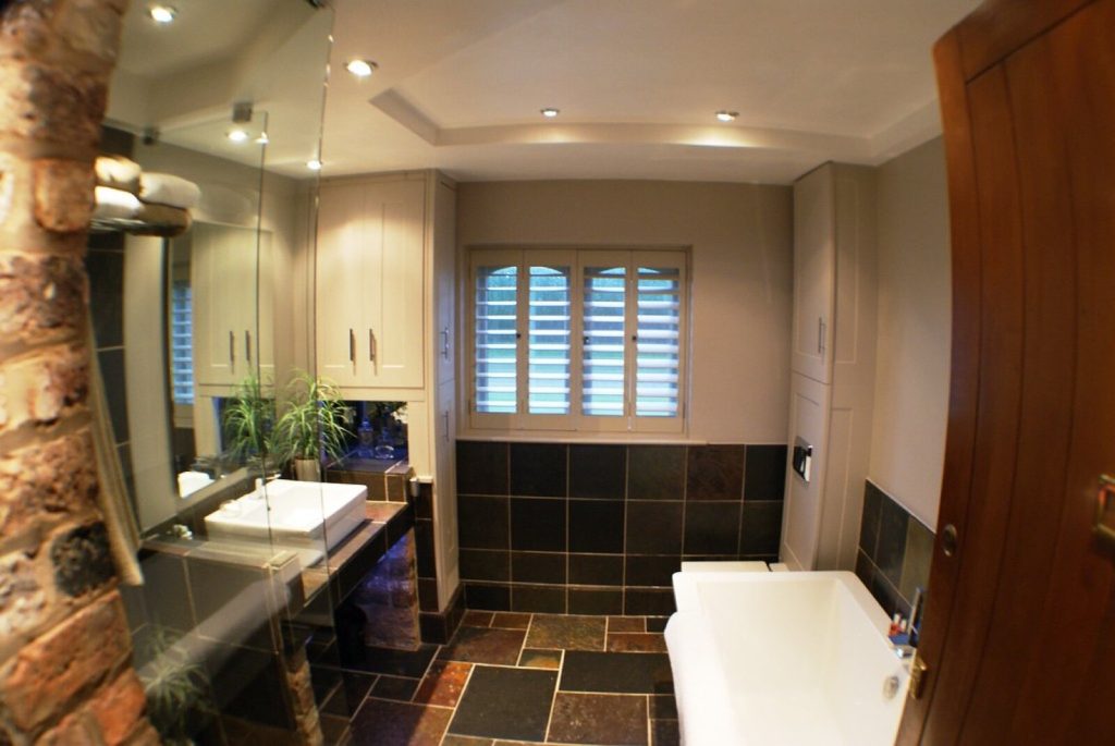 A finished tiled bathroom with dark floor tiles and visible grout joints