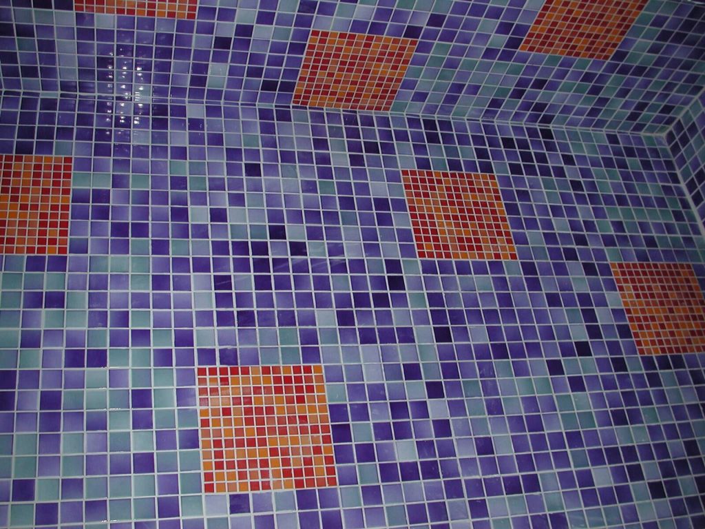 Mosaic wall and floor tiling with pale cement grout joints between small square tiles