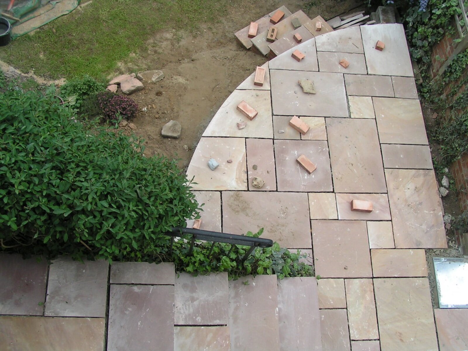 A garden patio part way through construction, with slabs set out and the joints still open