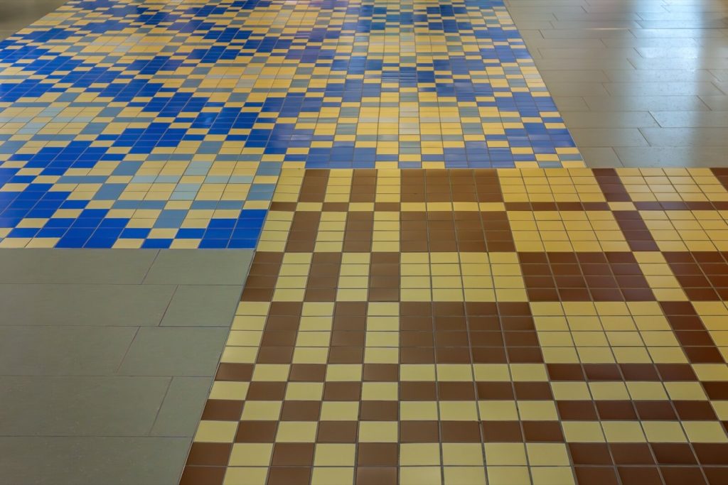 Ceramic floor tiles laid in a stack bond grid in blue, yellow and brown