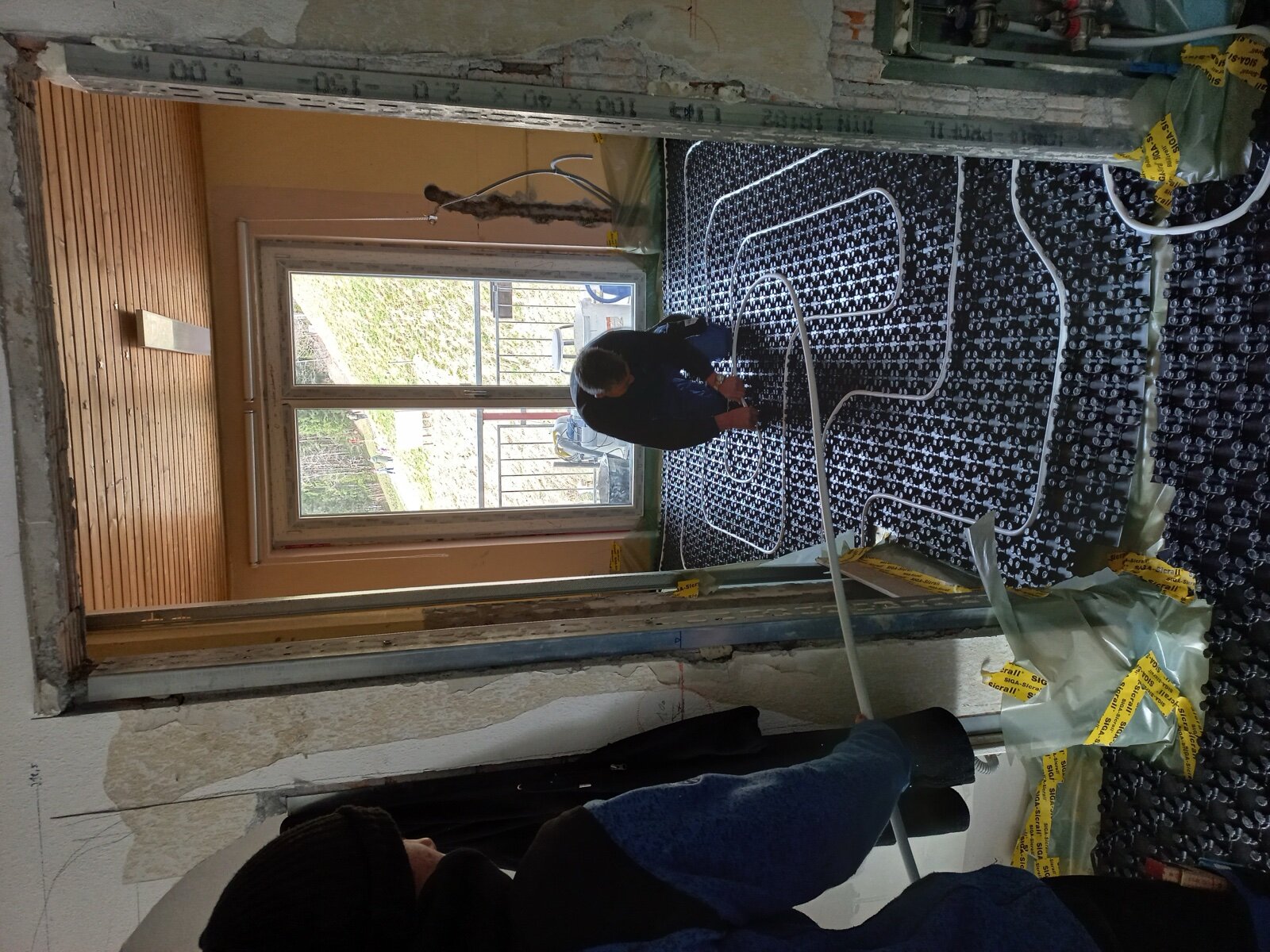 Underfloor heating pipework being laid on castellated panels before screeding