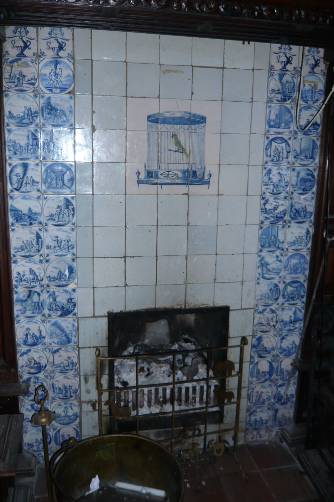 Fireplace surround tiled in blue and white Delft tiles with a small fire basket