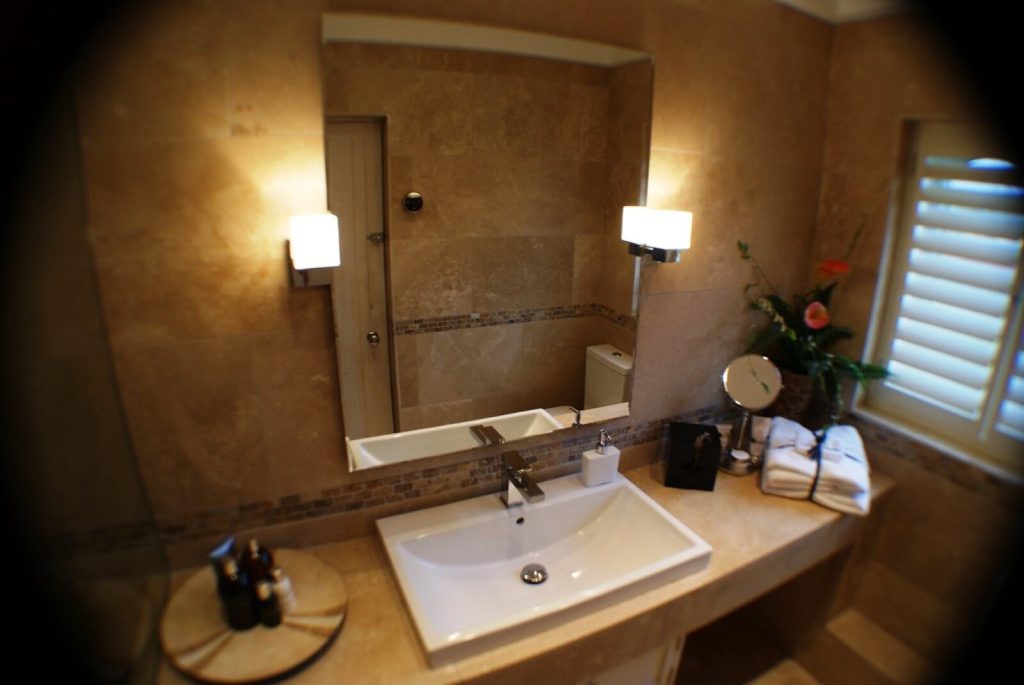 Travertine-tiled ensuite bathroom with a mosaic border above the basin