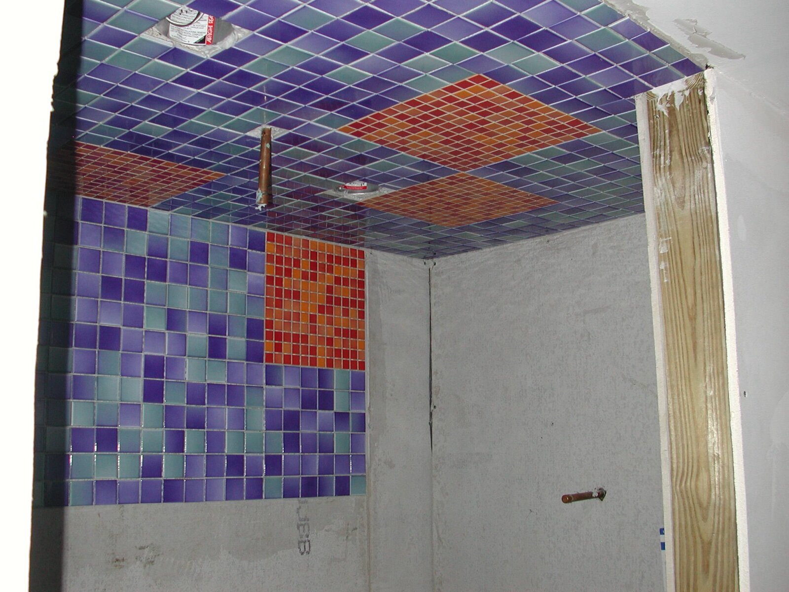 Part-finished mosaic tiling in a shower showing the internal corner where two walls meet