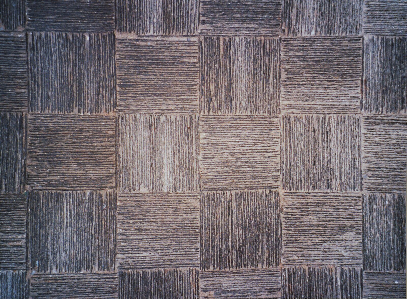 Square Cornish slate floor tiles with a grooved tooled surface laid in an alternating twill pattern