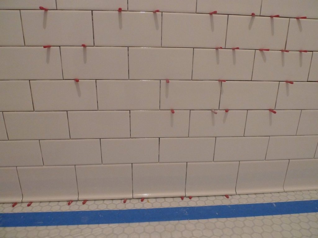 Metro wall tiles with red tile spacers standing in the grout joints