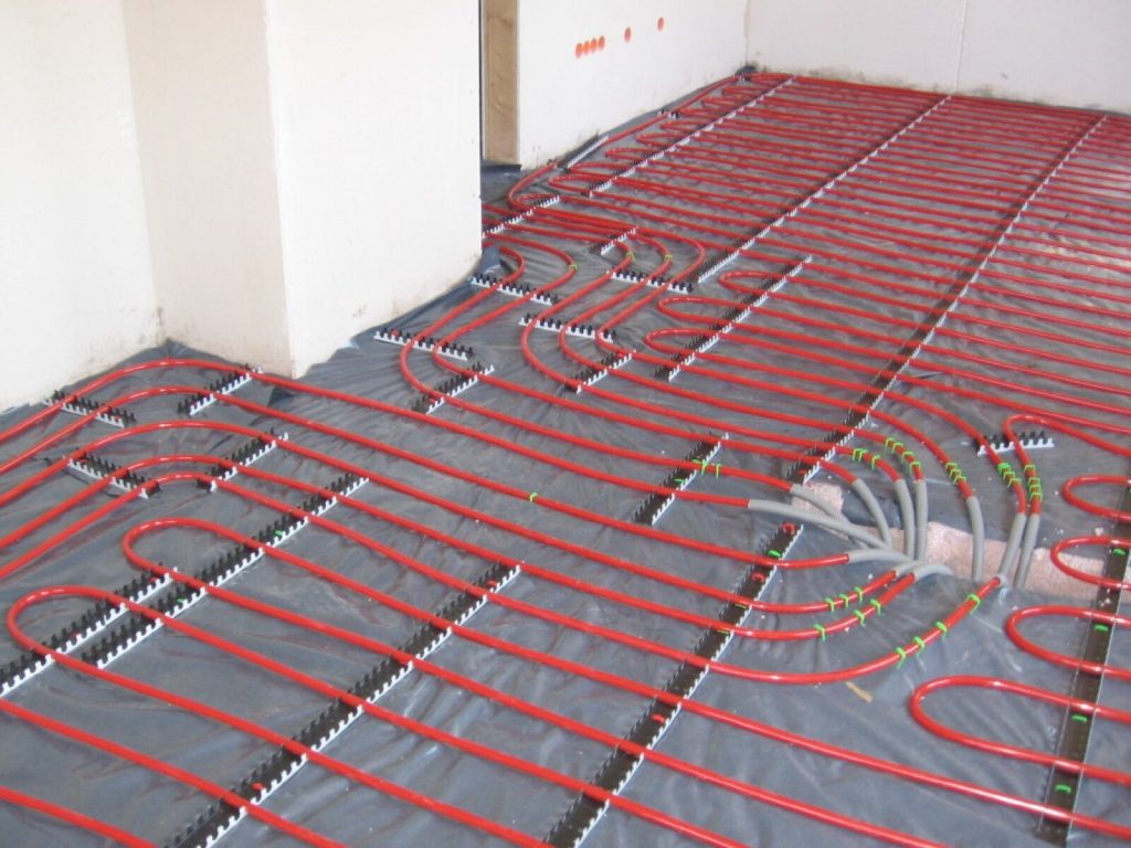 Red underfloor heating pipes clipped to insulation before screeding