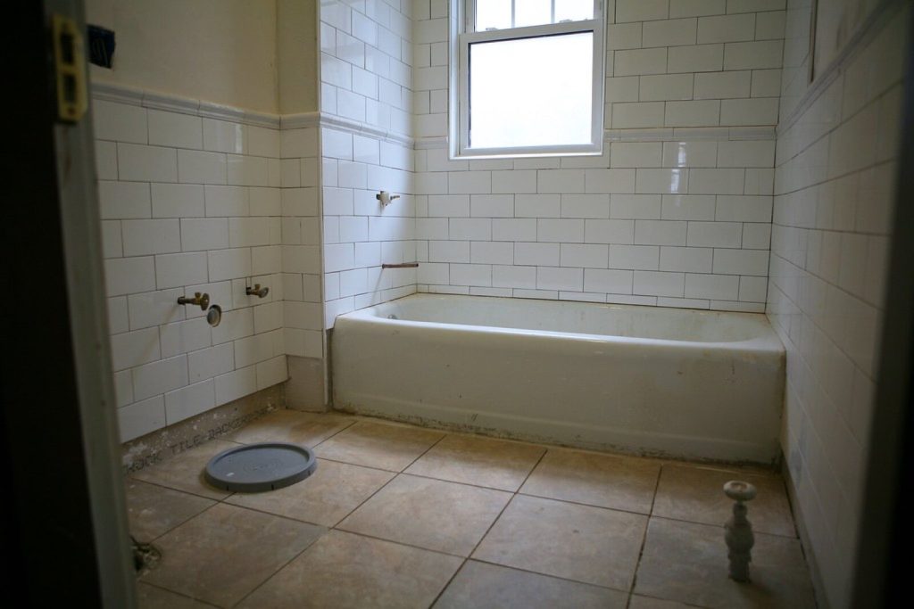 Bathroom with white metro wall tiles and a tiled floor part way through a refit