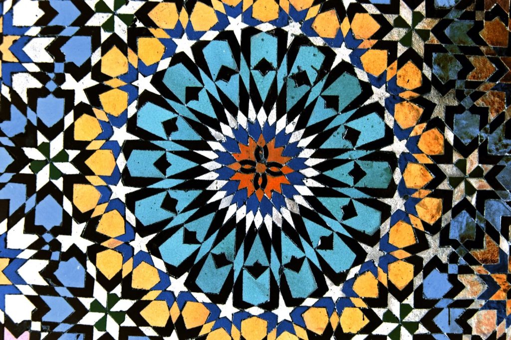 Geometric Moroccan zellige mosaic in blue, yellow, black and white around a central star