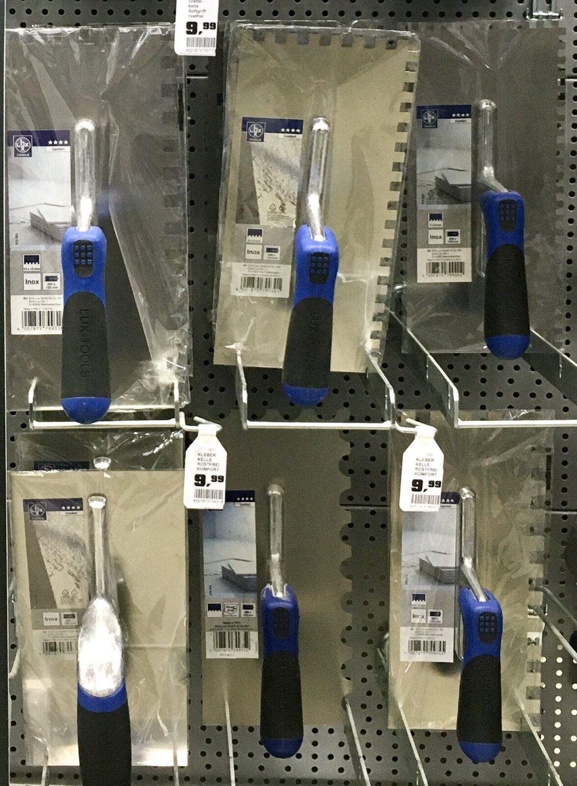 Square-notch tiling trowels in several sizes on a shop display