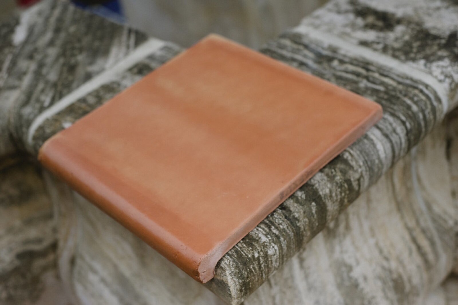 Terracotta bullnose step tile resting on a stone step